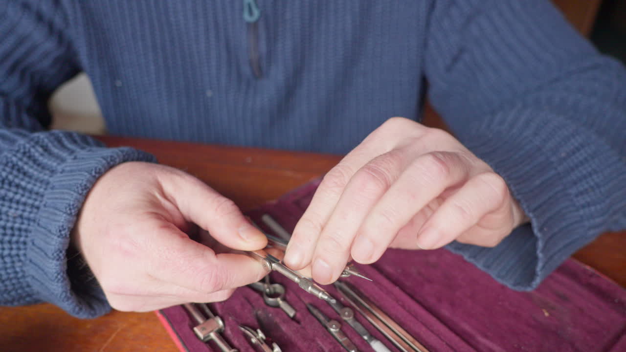 Medium shot of hands examining drafting tools in a fitted case, conveying careful inspection, quality control, and focused technical preparation