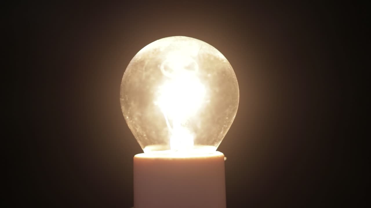 어두운 배경에서 빛나는 백열 전구의 정적 샷, 4k