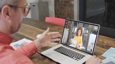 hombre de negocios caucásico en una llamada de video portátil con una colega afroamericana en la pantalla