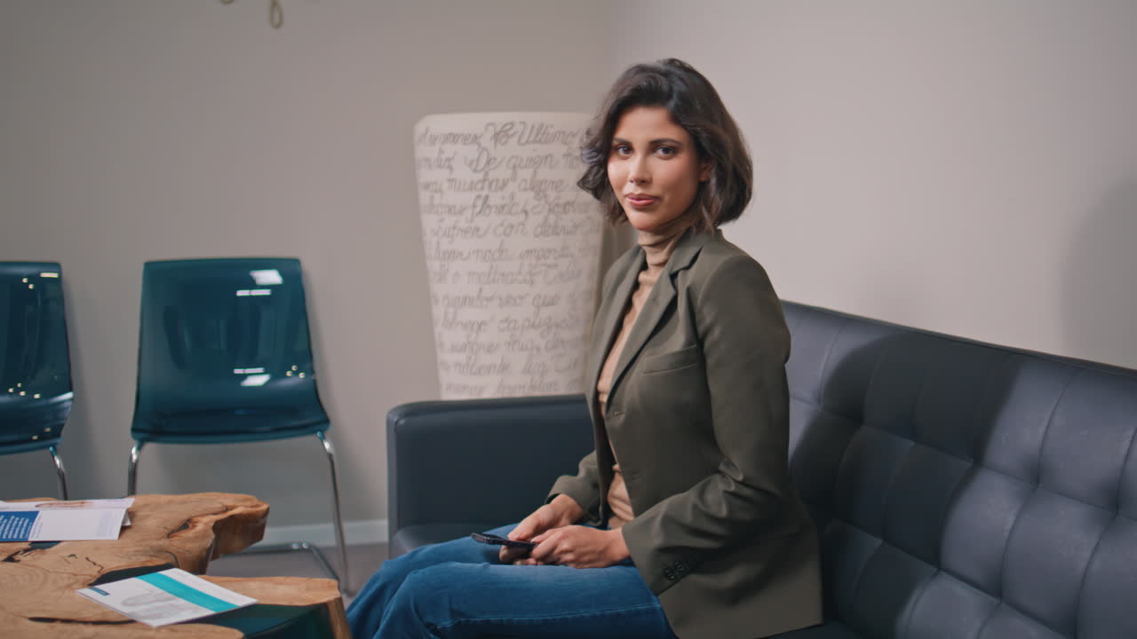 Mulher de negócios moderna terminando uma chamada no celular no saguão do escritório. Gerente elegante sentada.