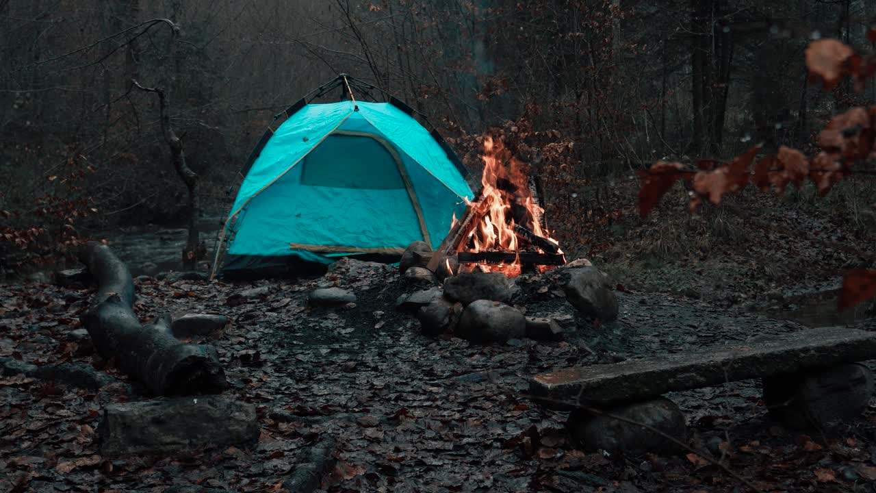 un campamento de otoño aislado con una tienda encendida y un fuego crujiente.