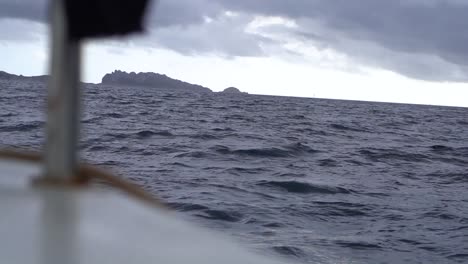 shot of the sea and an island from the deck of a sailboat during an overcast day