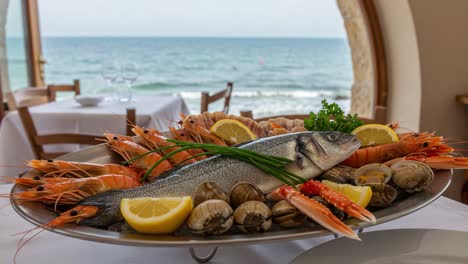 a lavish seafood platter with fresh fish, shrimp, and clams displayed on a table by the ocean, enhanced by bright lemon and green garnish
