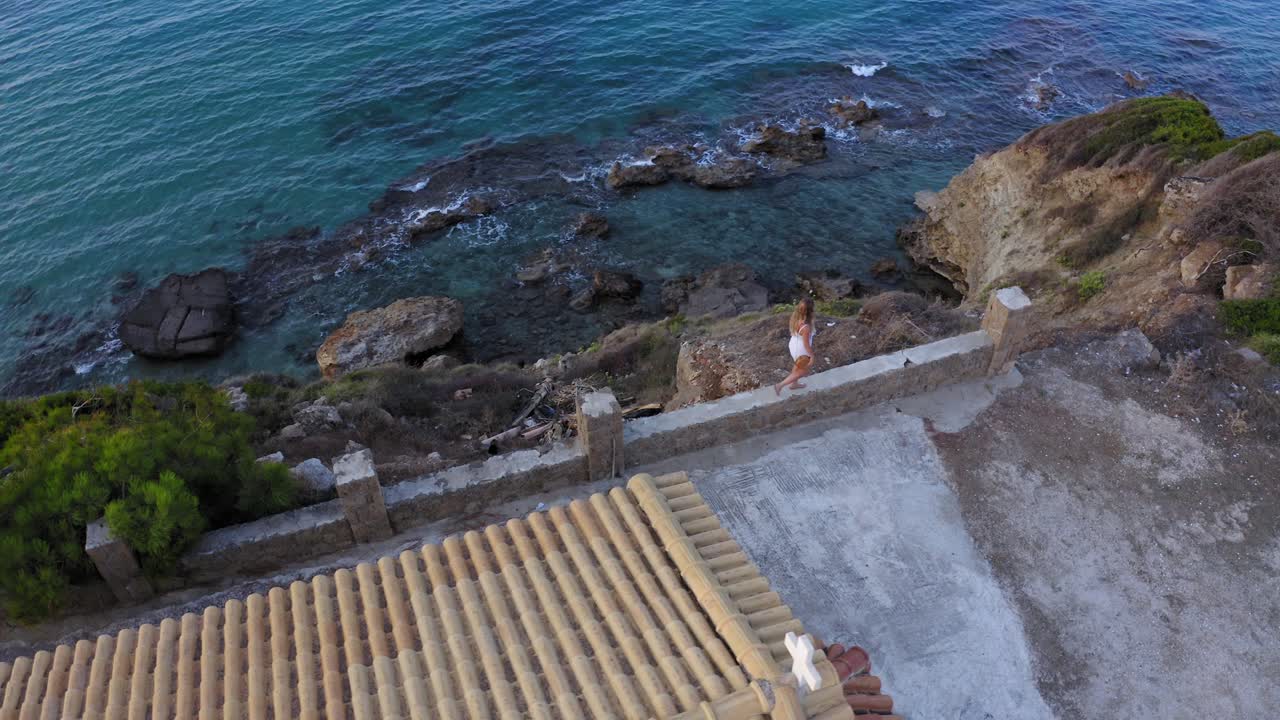 mujer se balancea descuidadamente sobre el borde del acantilado con una caída al océano