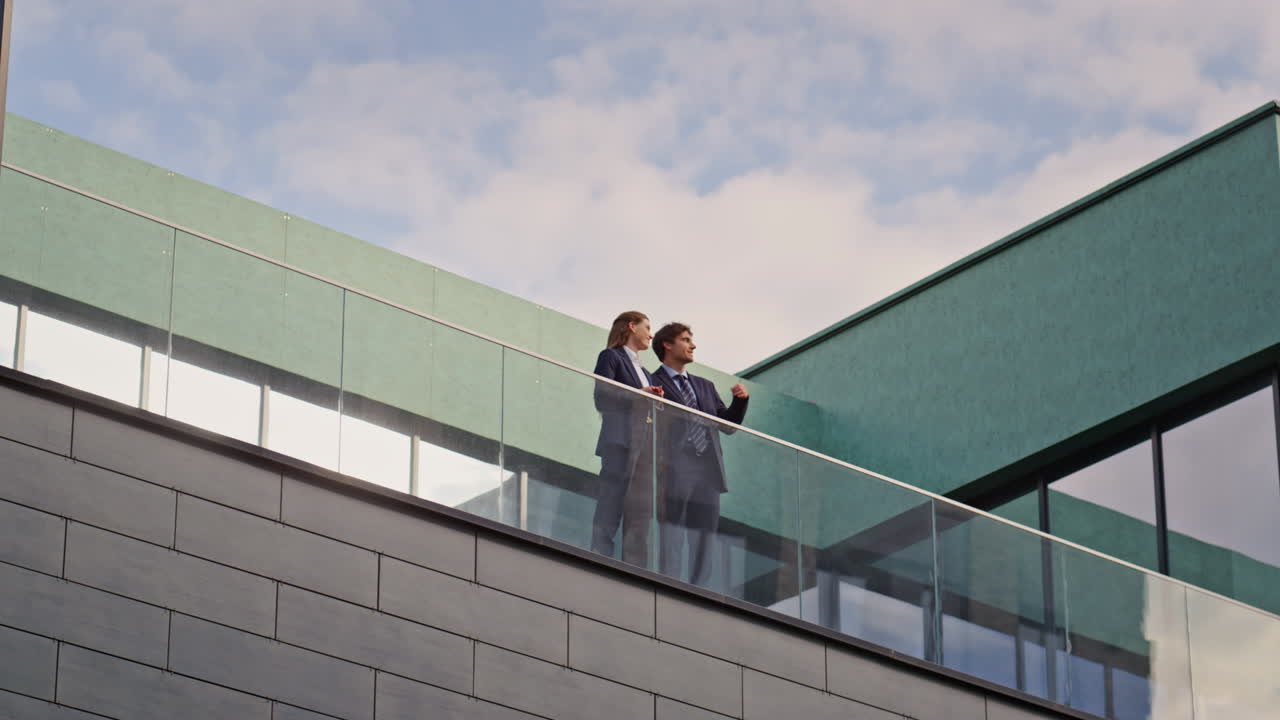 Confident business people communicating at rooftop balcony. Man woman talking