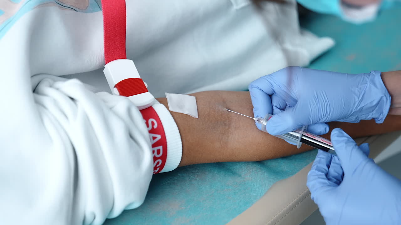 Gloved medic's hands using syringe to take the blood of a patient. Testing of blood from vein in hospital. Close up.