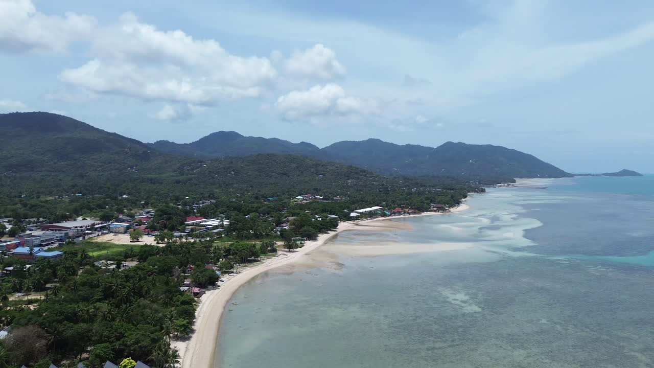 Aerial footage of Thong Sala Beach with a wide sandy shoreline, turquoise sea and lush tropical scenery on Koh Phangan island, Thailand