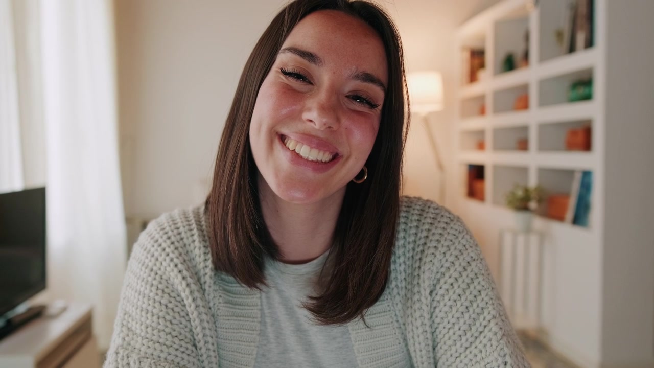 Giovane donna sorridente guarda verso la fotocamera in un accogliente interno domestico