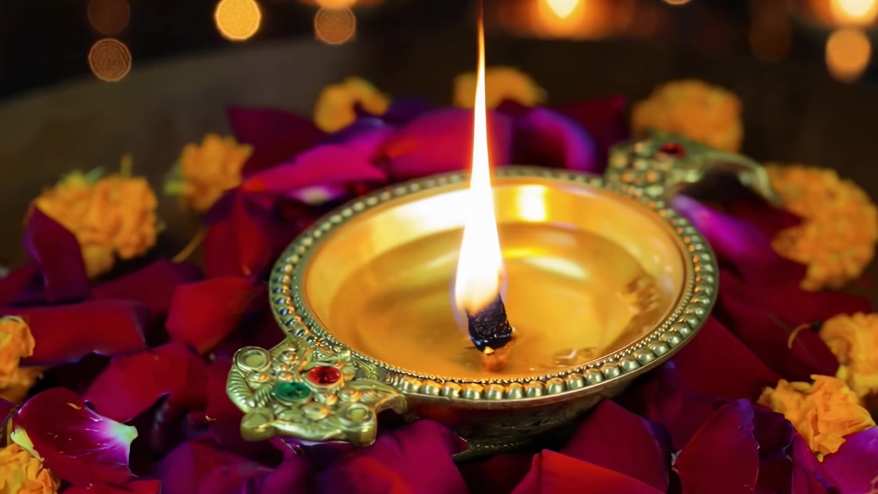 Traditionell indisk diya-oljelampa med fladdrande låga och rosenblad