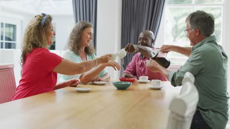 Animation-of-happy-diverse-female-and-male-senior-friends-drinking-coffee-at-home