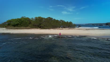 Luftdrohnen-Fliegen-Um-Eine-Frau-Herum,-Die-Im-Flachen-Felsigen-Meerwasser-Vor-Der-Strandküste-Von-Costa-Rica-Spaziert,-4k