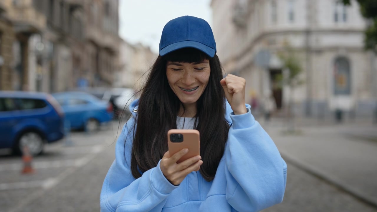 Donna felice che festeggia con lo smartphone in città