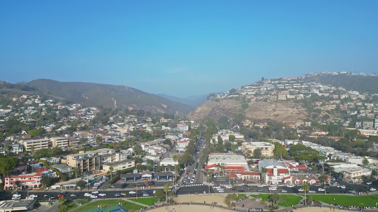 A drone shot of Laguna Beach, California, featuring basketball courts, houses, and buildings along the scenic coastline.
