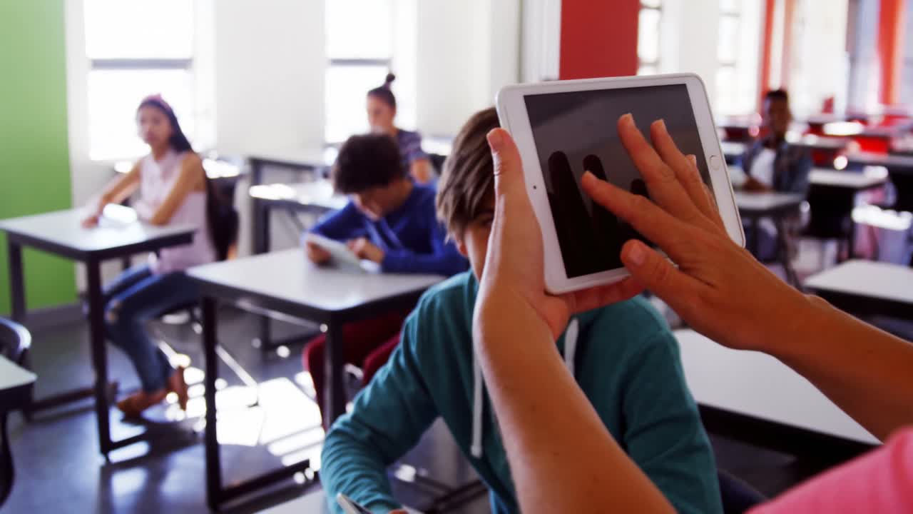maestro que enseña a los estudiantes en una tableta digital en el aula