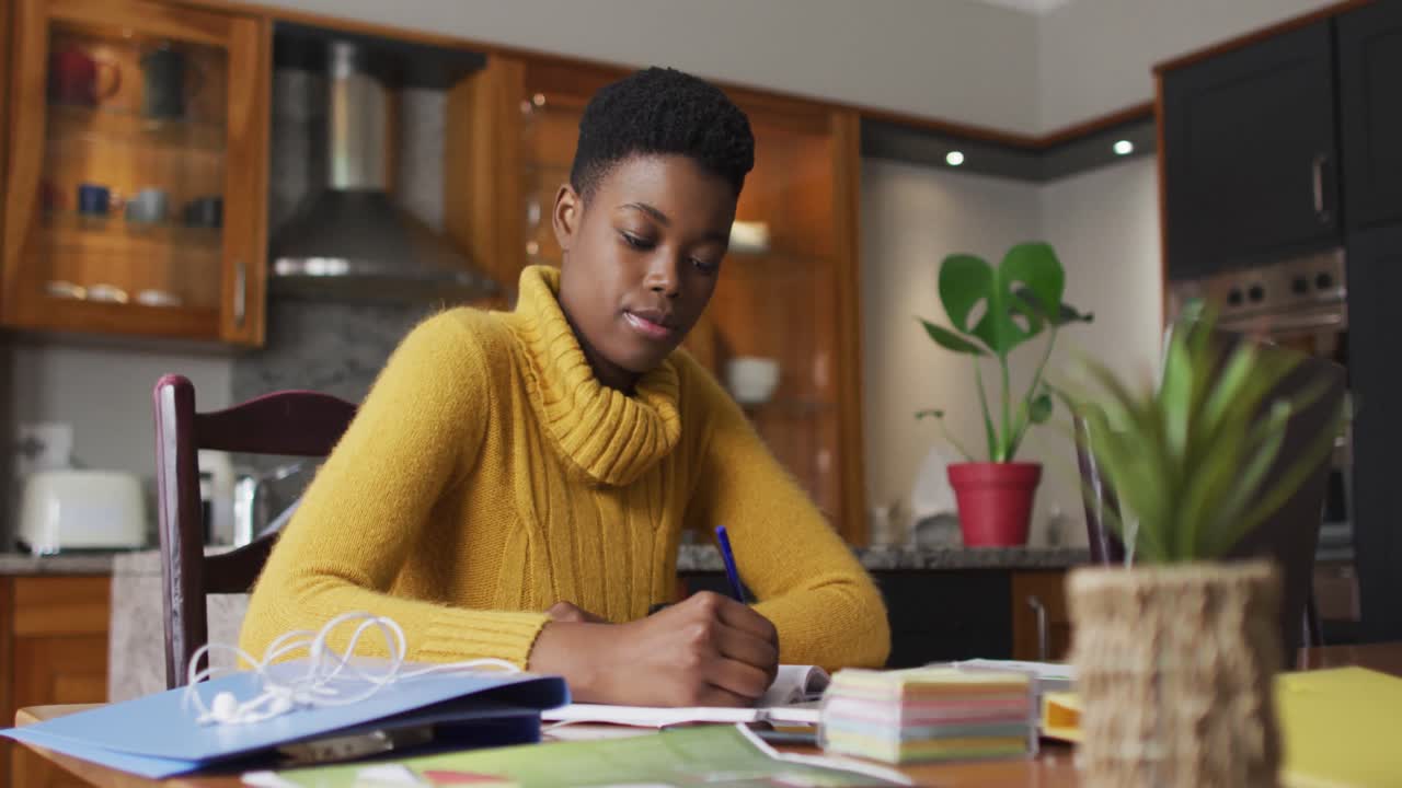 African american woman taking notes while working from home