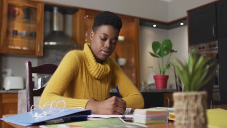 african american woman taking notes while working from home