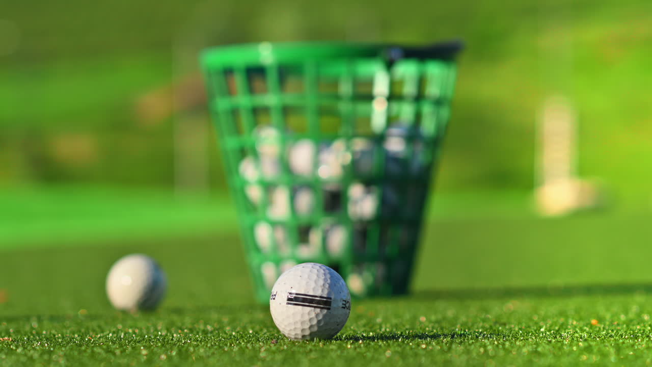 Primo piano di un secchio verde pieno di palline da golf su un campo, in una giornata di sole