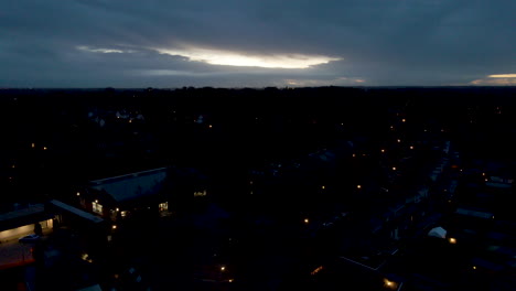 jib up over dark town in the early morning with the sun rising behind the clouds