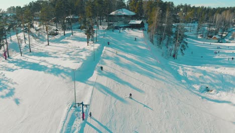 people ski and snowboard on mountain resort track upper view