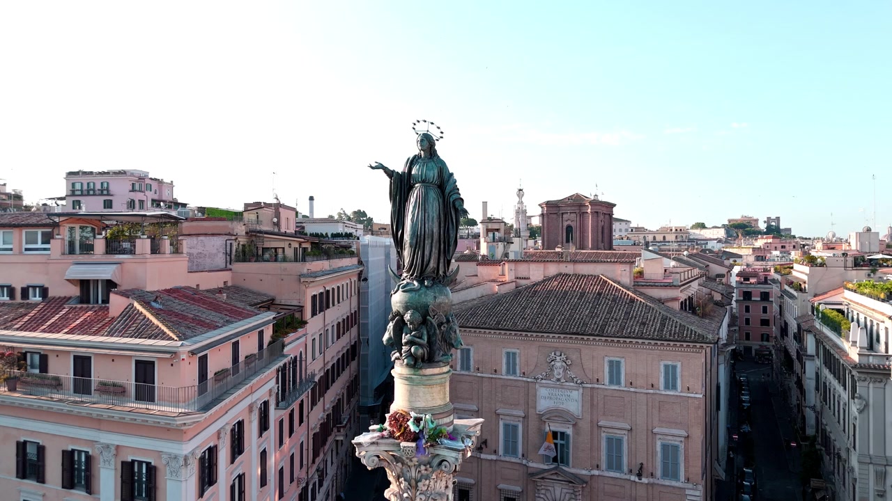 La statua della Colonna dell'Immacolata Concezione si erge sopra i palazzi circostanti mentre la telecamera si muove lungo una strada stretta