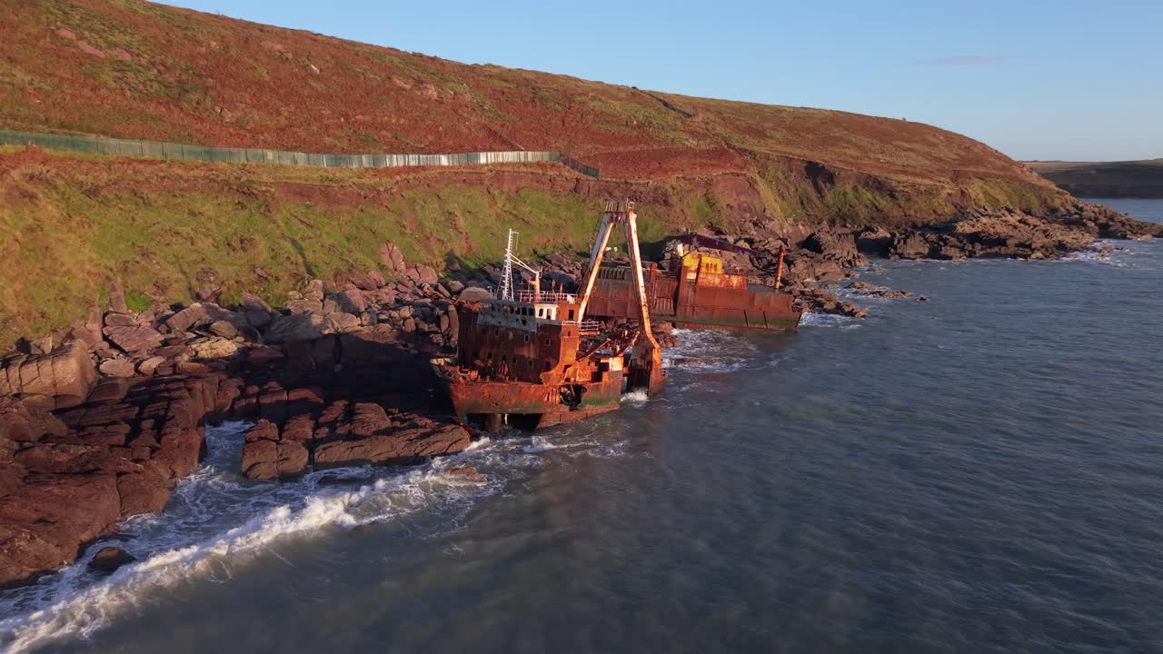 Fishing boat wreck on Ballycotton cliffs at golden hour, serene coastline in Cork, Ireland