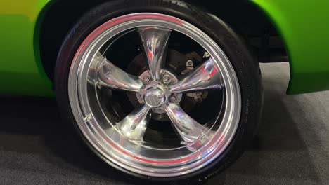 close-up of a shiny chrome five-spoke wheel on a green classic car
