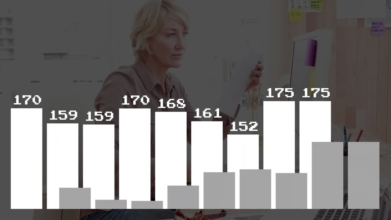 Animation of bar graph overlaying person working at desk with computer in school