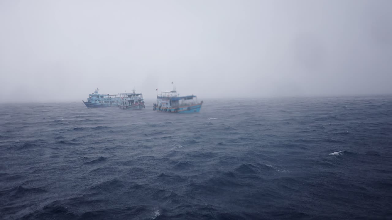 Two boats adrift on a stormy, foggy sea