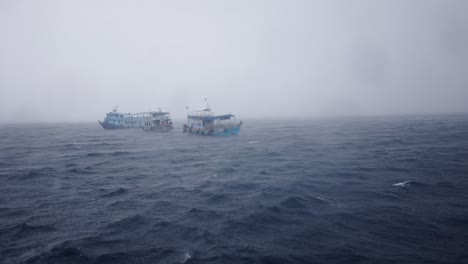 two boats adrift on a stormy, foggy sea