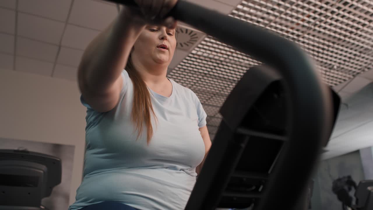 Donna in sovrappeso che si allena in palestra, ripresa dal basso.