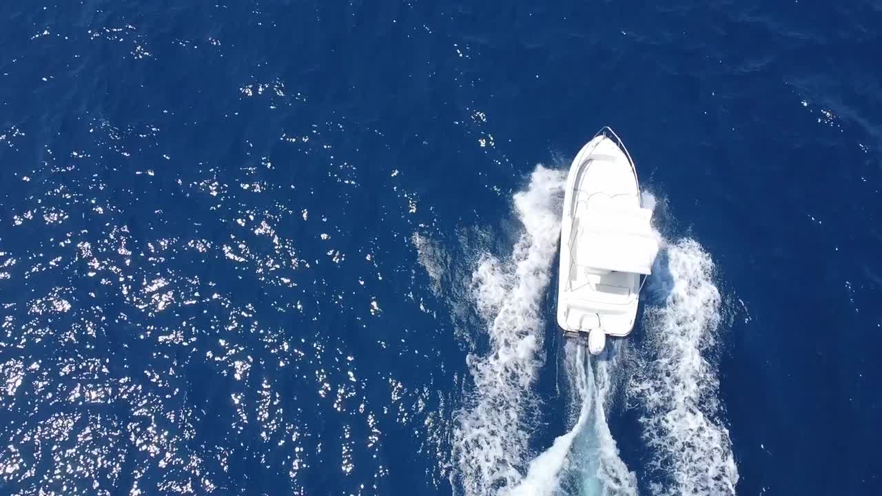 Motoscafo bianco che naviga attraverso le acque blu del Golfo di Castellammare vicino a Scopello, Trapani in Sicilia, Italia
