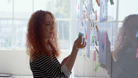 side view of young caucasian businesswoman working on glass wall in a modern office 4k