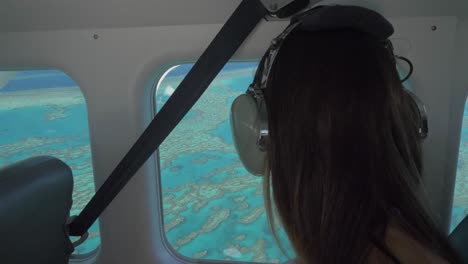 female traveler in a plane enjoying the aerial views of whitsunday islands in australia through glass window