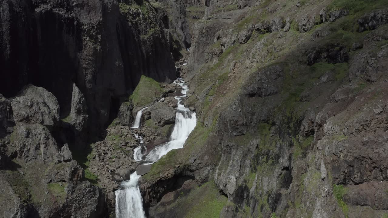 Secluded waterfall between steep cliffs in Iceland Graenafell, aerial