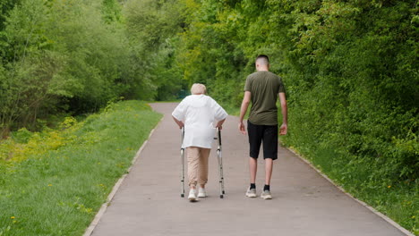 elderly woman with walker being assisted by a young man in a park