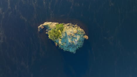 rocky outcrop in lake at sunrise with mist on lake surface curling around the island