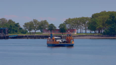 orange roll-on, roll-off ferry leaving the prison dock at hart island, with white prison bus