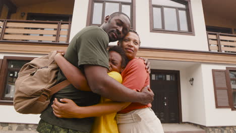 parents and son embracing each other outside home before army father going to military service