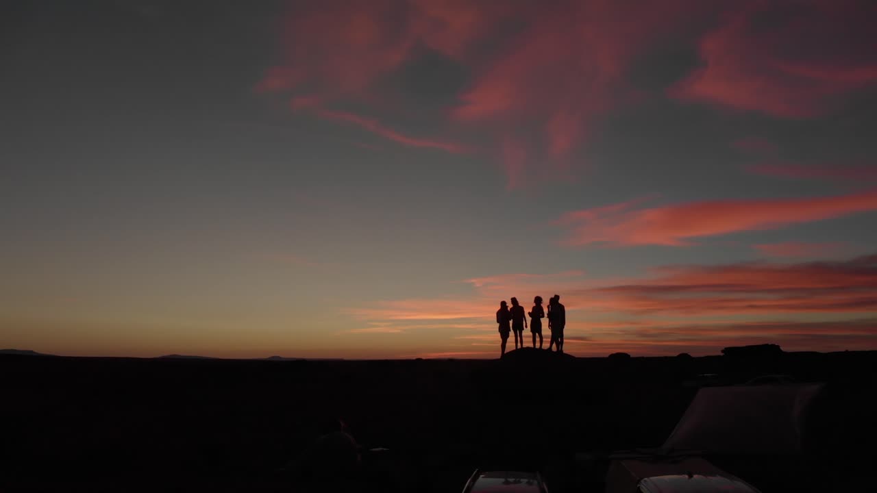 사막의 일몰에 대한 실루엣으로 친구 그룹에 의한 공중 비행
