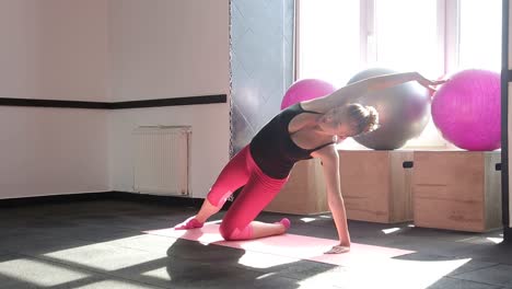 pregnant woman strokes belly while sitting on yoga mat happy pregnant woman sits on yoga mat and gently strokes belly in front of window future mom prepares to exercise and relax during yoga