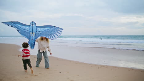 Mamá-Sonriente-Jugando-Cometa-Con-Un-Niño-En-La-Playa.-Padre-Alegre-Lanzando-Juguete