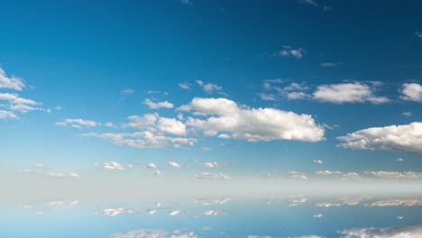 futuristic background consisting of time lapse clip of white fluffy clouds over blue sky and their reflection, video loop