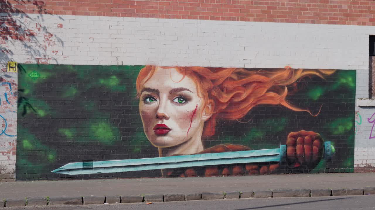 Levende vægmaleri malet på en bygningsmur, der forestiller en rødhåret kriger med et sværd, sat mod en urban gadebaggrund for virkningsfulde street art-billeder