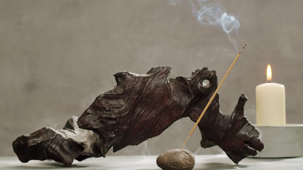 Person holding Palo Santo wood stick in hand, aromatic Palo Santo burning on black background, smoke spreading around, slow motion video clip, high quality 4k close up footage. High quality 4k footage