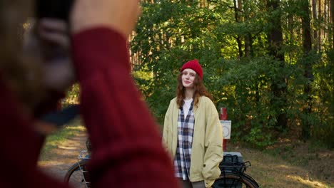 mujer con sombrero rojo en el bosque de otoño, siendo fotografiada