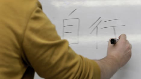 hand of male teacher writing cantonese on a white board