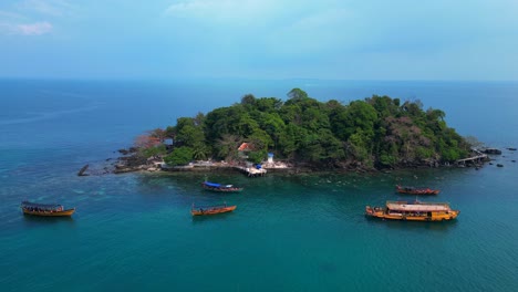 tourist boats surrounding a small tropical island in koh rong, cambodia, with crystal clear water and lush vegetation. nice aerial view flight drone panorama overview drone