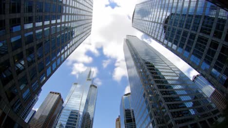 a captivating view from below the towering skyscrapers reveals the impressive architecture and bright blue sky. the sunlight reflects off the glass buildings, creating a stunning urban landscape.