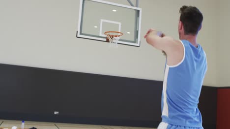 Kaukasischer-Männlicher-Basketballspieler,-Der-Ball-Auf-Korb-Schießt,-Training-Auf-Dem-Hallenplatz,-Zeitlupe