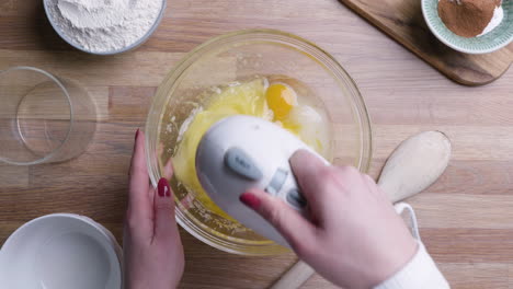 beating and whipping fresh eggs with sugar in a bowl with mixer for baking